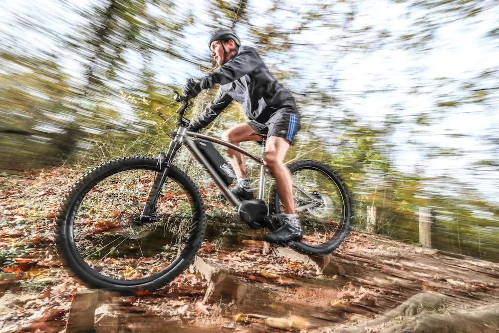 Person riding a mountain bike on a trail with blurred trees in the background

